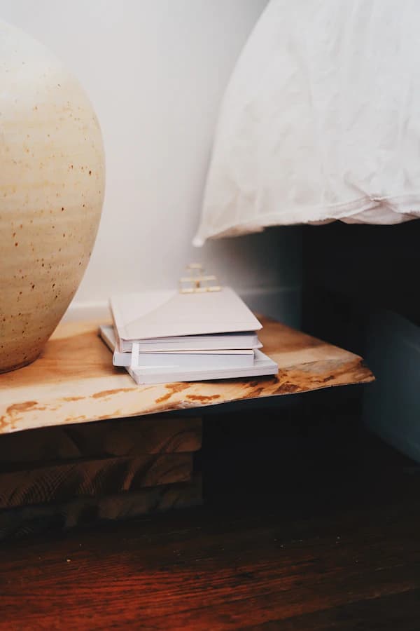 Une pile de livres près d’un grand vase en céramique sur une table en bois.