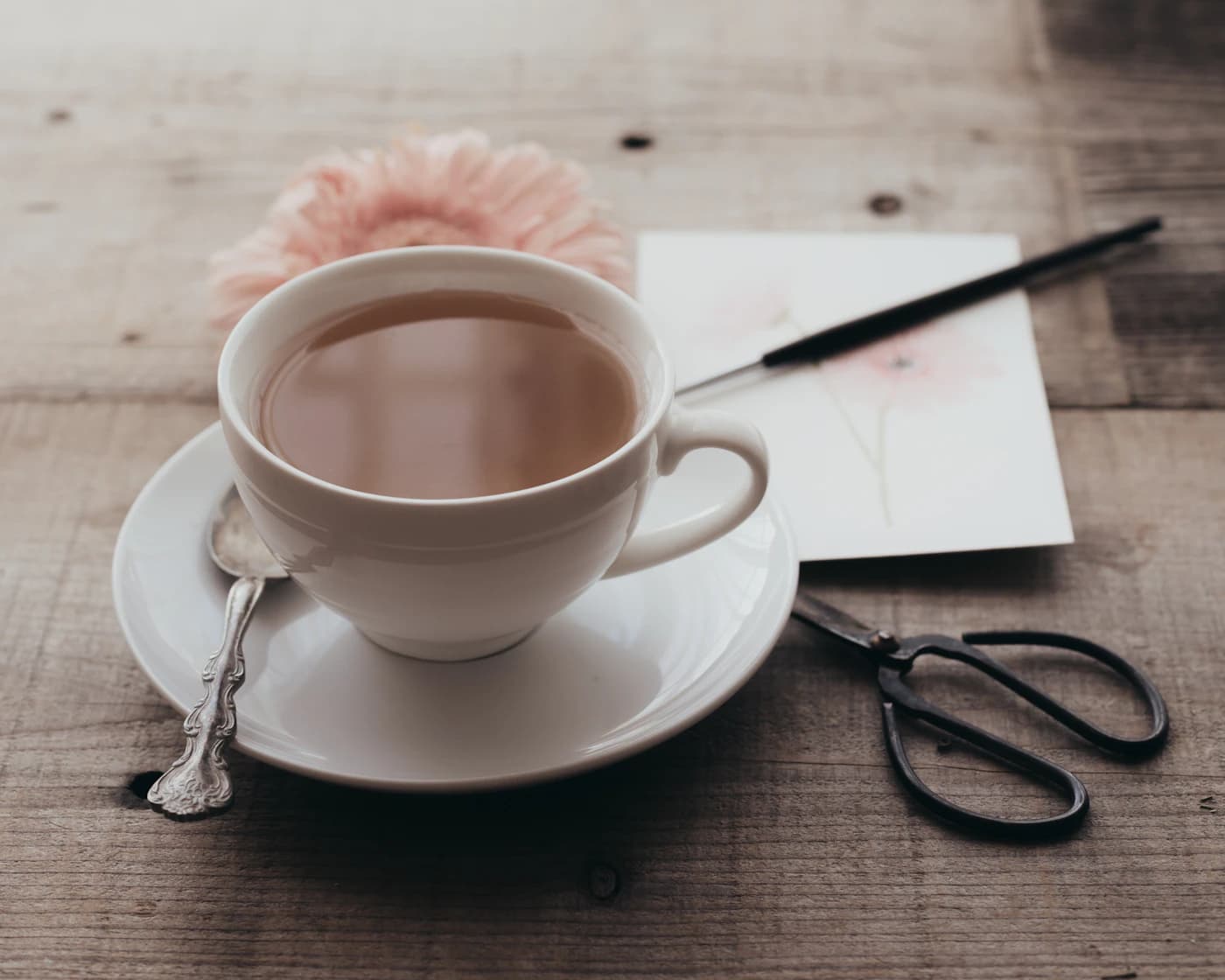 Une tasse de café sur une soucoupe près d’articles de papeterie sur une table en bois.